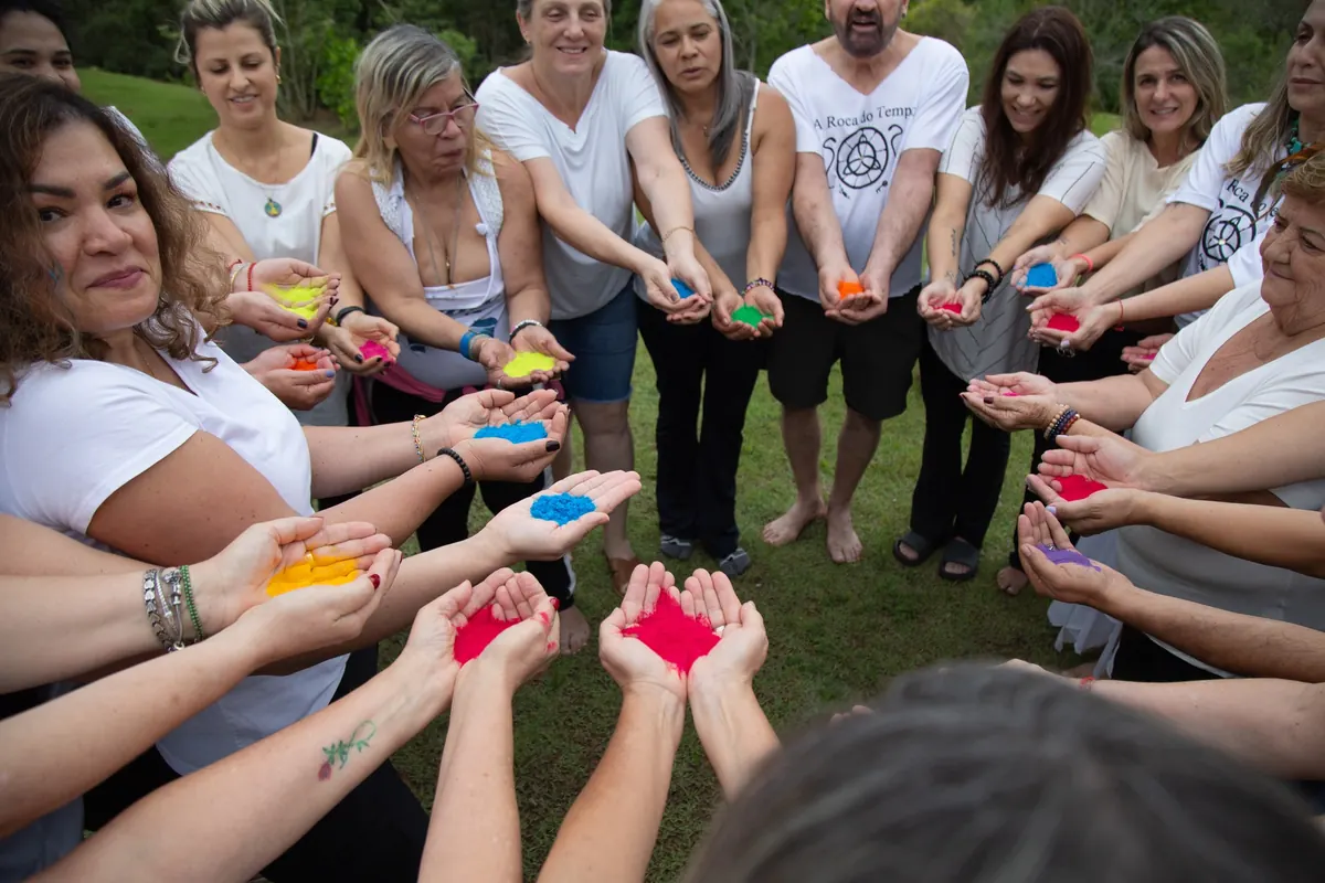 Mãos segurando pigmentos coloridos em uma dinâmica de grupo
